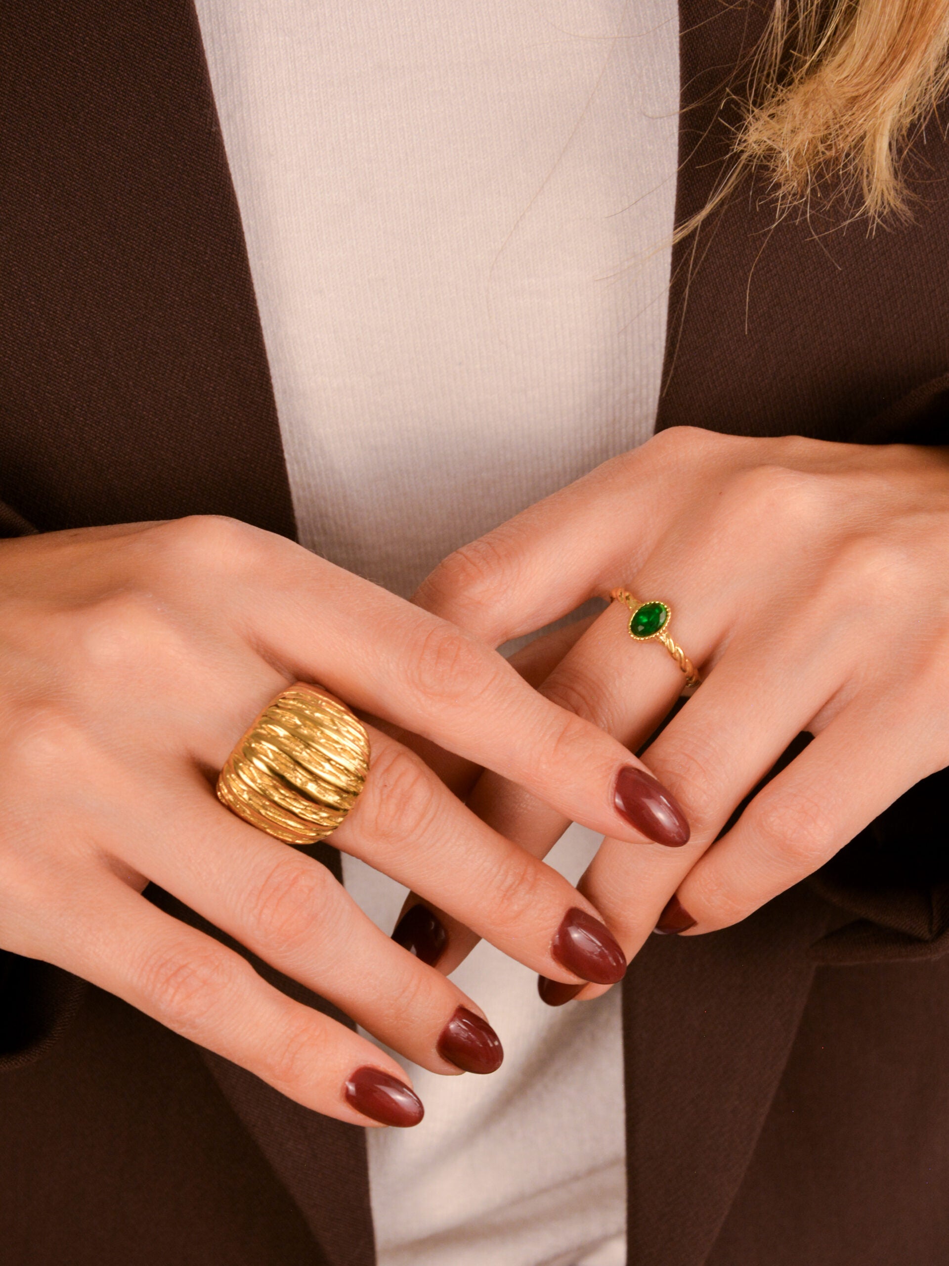 O Anel em Aço Dourado Torcido com Pedra Verde é uma verdadeira joia de presença — elegante, ousado e cheio de charme.